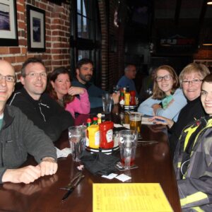 A group of eight people seated around a table in a restaurant, smiling at the camera.