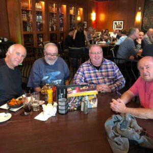 Four elderly men enjoying a meal together at a pub trivia night.